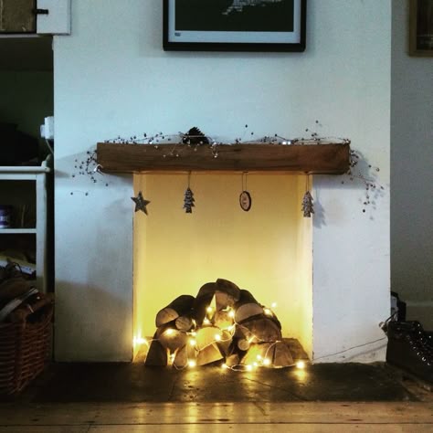 Christmas fireplace logs and fairy lights Unused Fireplace Lights, Fireplace Fairy Lights Ideas, Logs And Fairy Lights In Fireplace, Fairy Light Fireplace, Lights Inside Fireplace, Fireplace Fairy Lights, Logs In Fireplace Decorative, Fireplace Hole Ideas, Fairy Lights Fireplace