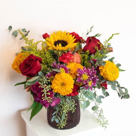 FALL in love with this charming floral arrangement. With beautiful Fall blooms and a touch of whimsy, this arrangement will add a playful touch to any space. Perfect for date nights, cozy evenings at home, or just surprising someone you love. Order now and FALL for its charm! Flower availability changes seasonally. Substitutions may apply. We promise your arrangement will be fresh and beautiful! Vase is subject to change Fall Flower Arrangements Centerpieces, Purple Fall Flowers, Fall Vase Arrangements, Fall Bouquet Flowers, Fall Wedding Flower Arrangements, Autumn Flower Arrangements, Thanksgiving Bouquet, Autumn Floral Arrangements, Floral Arrangements For Home