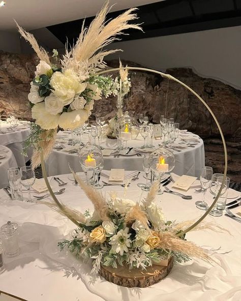 Enchanted Weddings Bristol on Instagram: "B O H O Wedding Decorations for the Table We just love this beautiful gold hoop floral table centrepiece with pampas grass and cream artificial flowers, with hanging glass bauble with tealight candles. In need of some help to get your wedding planning process started. Do get in touch with Carollyn to find out how my service can help! For enquires and to book your complimentary consultation please contact us on: #enchantedweddingsbristol ☎️(0117)9669 Wedding Table Hoop Centerpieces, Metal Centerpieces Wedding, Diy Table Centrepiece Wedding, Metal Floral Hoop Centerpiece, Pampas Hoop Centerpiece, Boohoo Baby Shower Centerpieces, Gold Hoop Floral Centerpiece, Single Hoop Centerpiece, Bautismo Centerpieces