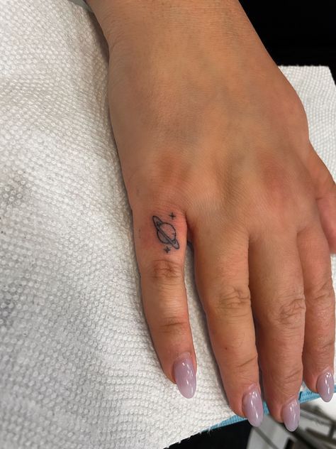 Tiny finger tat saturn tattoo space stars Universe Finger Tattoo, Star Finger Tat, Saturn Tiny Tattoo, Saturn Hand Tattoo, Mini Saturn Tattoo, Saturn Tattoo With Stars, Dainty Saturn Tattoo, Saturn Heart Tattoo, Saturn Finger Tattoo