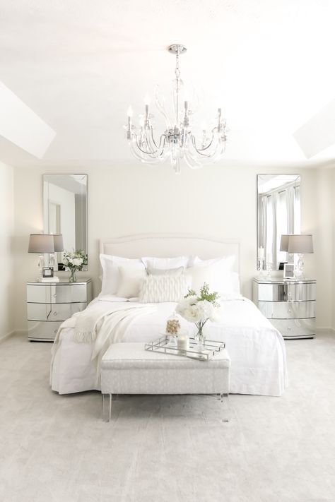 Mirrored nightstands, chandelier and all white bedding. You don't more glam than this! Bedroom With Mirrored Furniture, Mirrors Beside Bed Night Stands, White Bed Nightstand Ideas, Mirrors Next To Bed, All White Room Bedroom, White And Mirrored Bedroom Furniture, White Bedroom Set Ideas, Mirror Nightstand Bedroom Decor, All White Bedroom Ideas