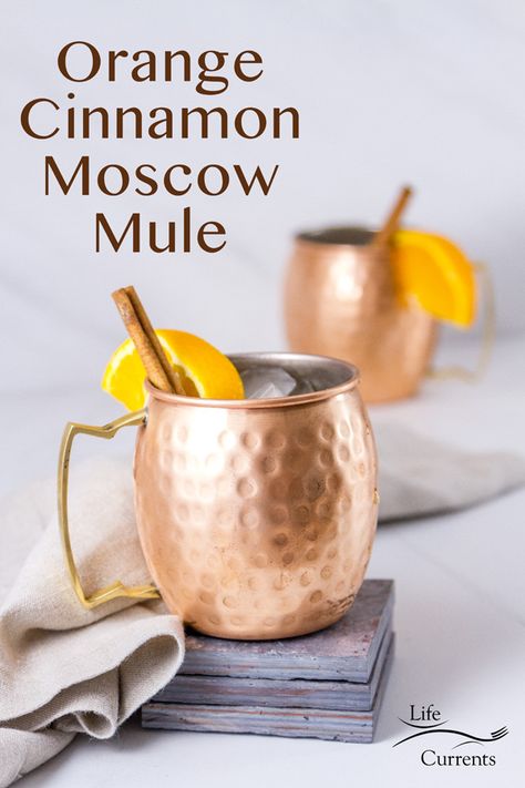 Two Moscow Mule drinks in copper mugs the front one is on a stack of grey tiles with a grey linen napkin and a title Spicy Ginger Simple Syrup, Cinnamon Vodka Cocktails, Orange Moscow Mule Recipe, Apple Cider Moscow Mule, Cinnamon Cocktail, Moscow Mule Drink, Cinnamon Simple Syrup, Spicy Drinks, Moscow Mules