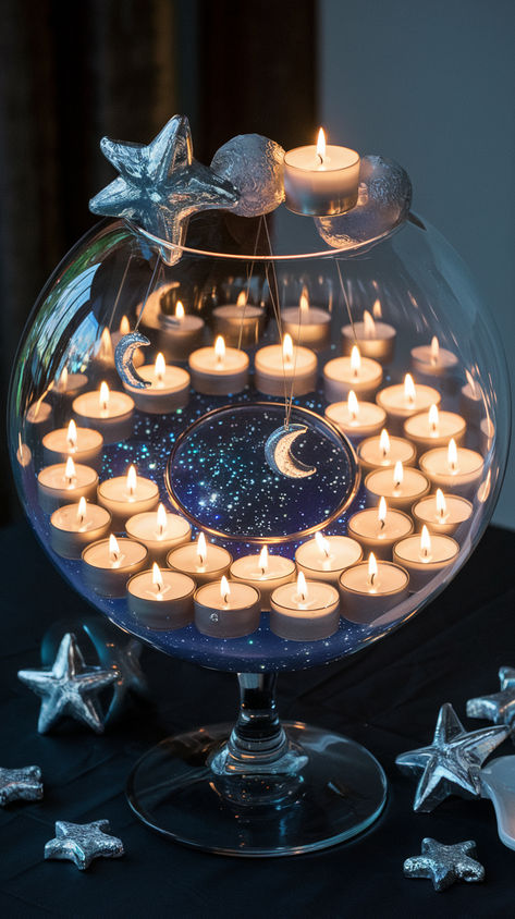 A large fishbowl style vase used for a celestial moon and stars themed wedding centerpiece. Candles and galaxial charms complete this decor idea. Moon Centerpiece Ideas Wedding, Under The Stars Quinceanera Theme Centerpieces, Galaxy Wedding Centerpieces, Written In The Stars Wedding Theme, Velaris Wedding Theme, Galaxy Wedding Decor, Moon Table Centerpieces, Sun And Moon Wedding Theme, Acotar Wedding Theme