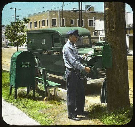 Letter carrier uses his key to unlock a mail collection box mounted to a telephone pole. A postal distribution box (used by mail carriers and clerks to store mail for neighborhood delivery) and a U.S. Mail truck are in the background. Hand-colored photographic print from 1947. Mail Truck, Mail Delivery, Marketing, Green