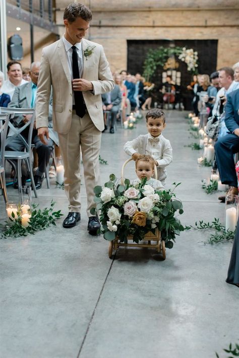 A young ring bearer gets pushed down the wedding ceremony aisle in a decorated wagon by an older ring bearer. The wagon has blush, white, and toffee roses, as well as eucalyptus provided by Romee Willow Florals. Ring Bearer Wagon, Wagon For Wedding, Wedding Cake Flowers, Ring Bearer Flower Girl, Cabin Wedding, Dog Wreath, Eco Friendly Wedding, Wedding Day Inspiration, Wedding Cakes With Flowers