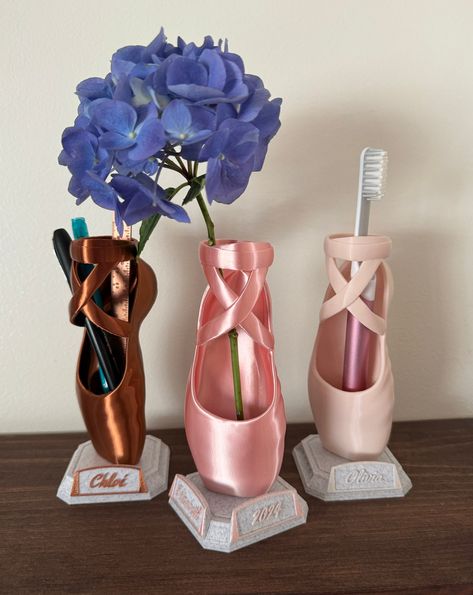 A great gift for the ballerina in your family.  These custom 3D printed shoes can be used as a toothbrush holder, small flower decorations, makeup brushes, pen or pencils, or whatever you decide. Dimensions with Base: 6.5" H x 3.5" W x 3.5" D Add a personalized name plate to your Ballet Shoe. Provide a name, year, or small message.  Each ballet shoe can have up to 4 different plates that can snap on or off. The color of the Text and border will match the shoe color chosen. Contact me about putti Pointe Shoe Decor, Ballerina Gift Ideas, Diy Dance Gifts, 3d Print Gifts, Shoe Vase, 3d Printed Gifts, 3d Printed Shoes, Small Flower Vase, Tooth Brush Holder