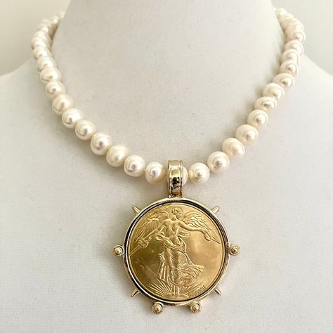 Fresh water pearl necklace with a Gold Reproduction French Commemorative  Medal Coin Pendant.   Necklace made up of  White Natural Freshwater Pearls 6-7mm. Available in 16in and 20in lengths.  High Lustre   Art Deco coin with an Antique style  Bezel. The coin is Brass, 22k gold plated, and measures 50mm including the Bezel  Pearl necklace available in 18in and 20in. The pendant can be removed and the pearls used with other pendants if desired.  A very versatile and different piece of jewelry A gorgeous gift or just a gift to yourself! Tips to keep your jewelry looking good. 1) Keep jewelry away from water and chemicals. 2) Remove during physical activities. 3) Store separately in a soft pouch or airtight box. 4) Avoid wearing to bed. 5) Gently polish with a soft, lint-free cloth to clean P French Coins, Iridescent Pearl, Gold Pearl Necklace, Freshwater Pearl Necklace, Bezel Pendant, Freshwater Pearl Necklaces, Keep Jewelry, Coin Pendant, Gorgeous Gift