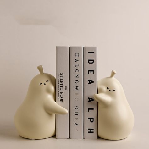 Introducing our stylish and functional pear-buddies book stand block! Made of high-quality ceramic in three beautiful colors - beige, yellow, and pink - this book block is a must-have for any book lover or design enthusiast. It is perfect for holding your favorite books and doubles as a decorative piece for any room in your home. Whether you're looking to organize your bookshelf or add a touch of creativity to your decor, our book stands block is the perfect solution. This book block's unique pe Cute Book Holders, Clay Bookshelf Decor, Ceramic Art Decor, Unique Home Diy, Clay Book Ends, Clay Book Holder, Ceramic Book Holder, Functional Ceramics Projects, Book Stand Ideas