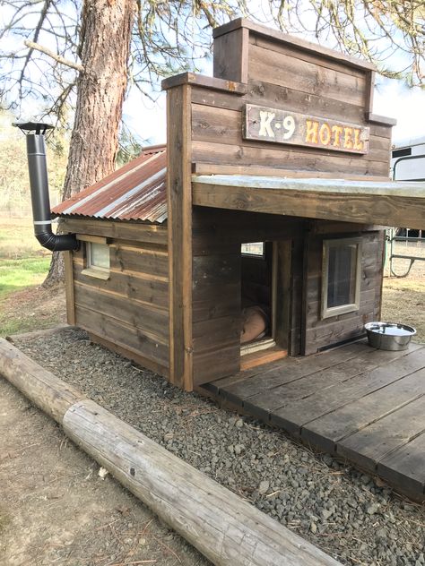 Remodeled our conventional doghouse to give it a rustic feel.  New front porch, false front with hand routed / painted sign, stove pipe, repurposed metal roof and wood siding.  The windows are from old campers and open for ventilation in the summer. We used a concoction of nails soaked in vinegar and applied it to the wood to give it that vintage look. Rustic Dog House, Doghouse With Porch, Painted Dog House, Tin Dog House, Dog House Pallets Diy, Doghouse Diy Outdoor, Dog Shed House, Rustic Dog House Outdoor, Wood Dog House Outdoor