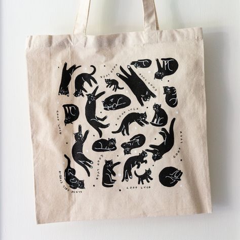 Limited edition of 50 heavy canvas totes with "GOOD LUCK" and black cats screen printed on one side in black and white. 16 x 15 in canvas bag This product is designed by me and printed sustainably by hand in Baltimore by Black Collar Press on 100% cotton totes made in the US Each item is shipped in a soft envelope. 10% of your purchase will be donated Cat Screen Print, Cat Tote Bag Design, Linocut Tote Bag, Lino Print Tote Bag, Canva Business Ideas, Black Tote Bag Design, Cool Tote Bag Design, Canvas Tote Bag Design, Cat Shirt Design