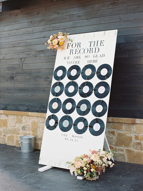 White painted plywood wedding seating chart with each table grouping printed on record label. At the top of the seating chart reads “for the record we are so glad you’re here” with floral trims Record Table Decor Wedding, Wedding Vinyl Ideas, Diy Wedding Table Seating Chart, Records Wedding Decor, Vinyl Seating Chart Wedding, Record Wedding Decor, Record Seating Chart, Lp Seating Chart Wedding, Record Charger Plates