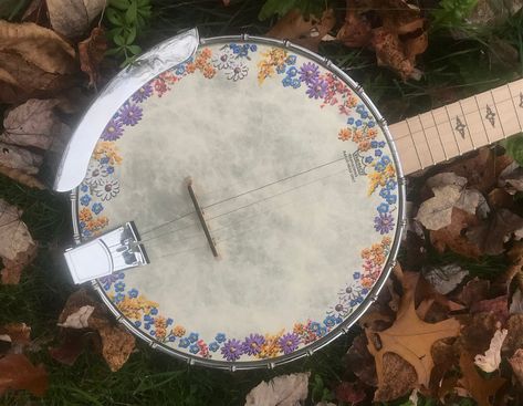 "This nicely finished, full-size Mulucky brand open back banjo is all maple with a very natural looking Remo Weatherking head. I add my colorful hand-painted wildflower meadow design around the edge of the top, protected by a coat of matte varnish. Matching flowers on the headstock complement the main design and are protected by a satin varnish that matches the rest of the instrument. This five-string banjo has great resonance and the open back allows action height to be easily fine-tuned with the accessible tensioner. Weight is also less than a resonator style banjo. (NOTE: \"Custom head only\" option is just for the cost of me painting a new banjo head cover that you ship to me. It does not include either the  head head itself or a banjo) Includes a nicely-padded gig bag, extra strings, Banjo Aesthetic, Homemade Instruments, Wildflower Meadow, Guitar Art, I'm With The Band, April 4, April 13, Cool Guitar, Kinds Of Music