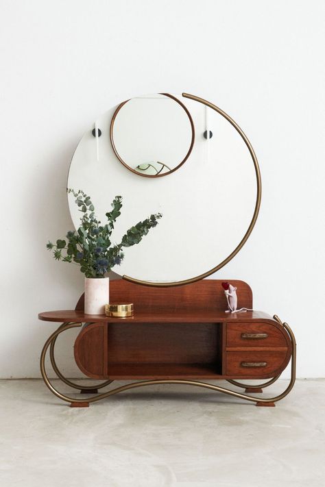 The swirling curved metal frame that supports the piece is a standout feature. A large circular mirror is wrapped around by the curved metal frame, creating a sense of continuity and harmony in the design. The teak wood body of the vanity also features curved lines and a circular motif, adding to the overall sense of balance and harmony in the design. The original brass handles add a touch of vintage charm and elegance to the piece. Circa 1920s-1930s Curved Vanity, Asian Furniture, Circular Mirror, Modern Furniture Stores, Curved Lines, Brass Handles, Unique Furniture, Designer Furniture, Signature Design