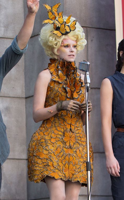 Elizabeth Banks gets to play major #fashion dress-up in the Hunger Games movies, like this butterfly dress with 10,000 hand-painted feathers! Alexander Mcqueen Butterfly Dress, Hunger Games Effie Outfits, Hunger Games Butterfly Dress, Capitol Couture Hunger Games, Hunger Games Effie Costume, Effie Hunger Games Outfits, Hunger Games Dresses Gowns, Effie Butterfly Dress, Effie Trinket Cosplay