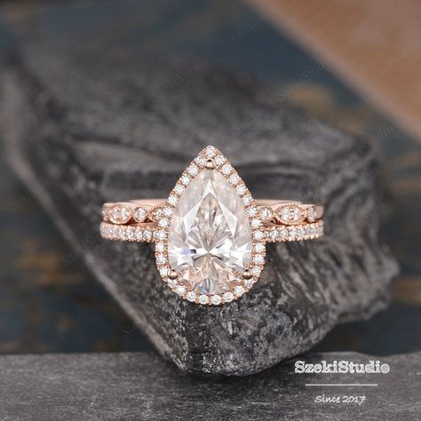 "3.5ct Pear Cut Moissanite Engagement Ring Set Pear Shaped Wedding Ring Rose Gold Bridal Set Tear Drop Halo Ring 8x12mm Moissanite Ring Engagement ring: https://www.etsy.com/listing/619649224 Wedding band: https://www.etsy.com/listing/551290406 6*8mm bridal set: https://www.etsy.com/listing/607354156 ITEM INFORMATION Metal Type - Solid 14k Rose Gold Band Width - (approx. 1.5mm) **Engagement Ring** Center Stone - 8*12mm Moissanite, Pear Shaped Weight- 3.5CT Color- D-E-F Clarity- VVS Side Stone - Pear Shape Rose Gold Engagement Ring, Tear Drop Engagement Ring Gold Band, Tear Drop Wedding Ring Sets, Pear Bridal Set, Pear Engagement Ring With Wedding Band Gold, Rose Gold Pear Shaped Engagement Ring, Pear Wedding Ring Set Gold, Tear Drop Engagement Ring Set, Pear Shaped Wedding Set