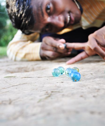 Kancha was one of the most popular games among children in the neighbourhood. It is played using marbles called ‘Kancha’. The players are to hit the selected target ‘kancha’ using their own marble ball. The winner takes all Kanchas of rest of the players. Indian Games, Playing Marbles, Village Games, 90s Games, Indians Game, Childhood Photography, Marble Ball, Memory Pictures, Traditional Toys