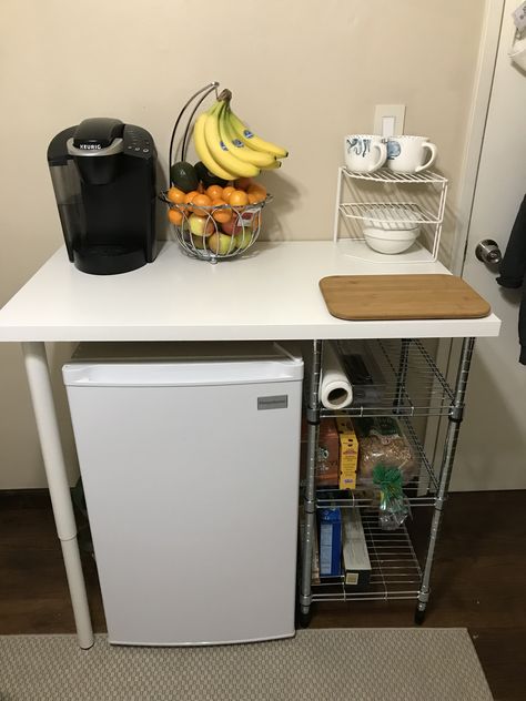 Mini fridge storage idea  IKEA desk top— $8.99 IKEA adjustable legs (2)— $30.00 IKEA food storage shelf— $18.99 KEYSTONE white mini fridge— $149.99 Shelf For Mini Fridge, Room Food Storage Ideas, Dorm Dishes Storage, College Mini Fridge Food, Studio Apartment Mini Fridge, Mini Fridge And Microwave Stand, Dorm Fridge Stand, Dorm Room Ideas Mini Fridge, Mini Desk Fridge