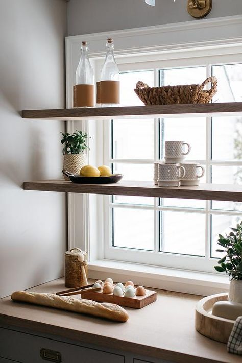 Stacked wood floating shelves are mounted in front of a window in a light gray kitchen pantry boasting light gray cabinets finished with vintage brass library pulls and a wooden countertop. Shelf In Window, Shelf Over Kitchen Window, Shelves Over Windows, Shelves In Front Of Window, Shelves In Front Of Kitchen Window, Shelf Over Window, Kitchen Window Shelf, Kitchen Window Design, Kitchen Floating Shelves