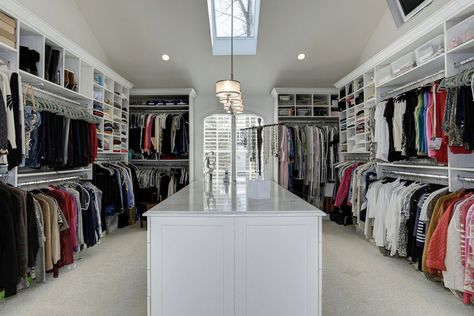 A massive walk-in closet with lots of open storage, showcasing the array of clothes and other items in the room. This much clothing could be overwhelming with all the different colors and textures, and to help tone it down, the cabinets and the rest of the room are all white. There’s a combination of hanging racks and open shelves,  creating a good variety of storage for all your needs. It also has a large island counter in the middle which also has more drawer &  cabinet storage. Small Master Closet, Walk In Closet Ideas, A Walk In Closet, Master Closet Design, Closet Island, Grand Dressing, Dressing Design, Dressing Room Decor, Huge Closet