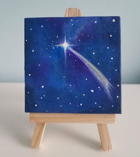 Small easel paintings make the perfect gift for every occasion! They can be displayed easily on a shelf, desk or countertop. Each painting is an original work of art. This painting show a shooting star in the galaxy night sky, with lots of stars and shades of purple and blue colors.  The 3" by 3" stretched canvas is prepared with several layers of white Gesso, and sealed with three coats of matte varnish. Each painting is carefully detailed, and continues to the sides of the canvas.  The wooden Simple Acrylic Paintings Night Sky, Stars In The Sky Painting, Comet Painting Easy, Small Blue Paintings, Mini Galaxy Painting, Painting Ideas Night Sky Easy, Painting Night Sky Easy, Sky Night Painting, Painting Stars Acrylic