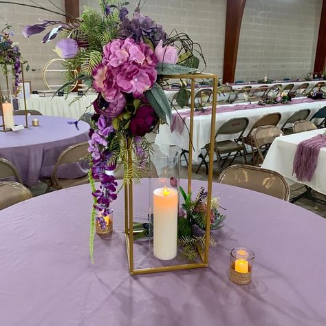 Brighten up your wedding tablescapes with chic table centerpieces and ooze magical flair all around. Dress up the tables in lavender tablecloth and create a visually appealing effect of height and dimension by setting gold flower stands decorated with a purple & lavender hued hydrangea, peonies, orchid stems, wisteria vines, & greenery spray flower arrangement. Highlight the majestic appeal of your tablescape by arranging LED pillar candles and votive candles in honeycomb base candle holders. Wisteria Table Decorations, Wisteria Centerpiece, Lavender Centerpieces, Wisteria Vines, Event Decor Ideas, Party Decorations Table, Vines Flowers, Thanksgiving Breakfast, Lantern Centerpieces