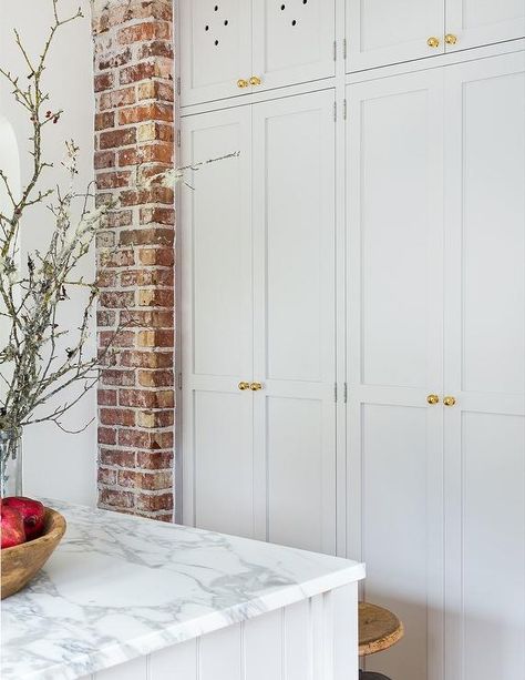 Floor to ceiling cabinet for bulky storage (vacuum, broom, xmas tree). Floor to ceiling white shaker kitchen cabinets accented with antique brass knobs. Brass Knobs Kitchen, Kitchen Cabinets To Ceiling, Heidi Caillier, Cabinets To Ceiling, White Shaker Kitchen Cabinets, Floor To Ceiling Cabinets, White Shaker Kitchen, Shaker Kitchen Cabinets, Brick Kitchen