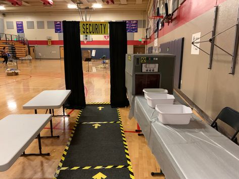 Entrance rugs sere taped down with caution tape/ tables covered with silver table cloths, large box with duct tape “flaps” to slide boxes through (Allowed us to make sure they brought water bottles and added  other supplies as it passed through the “scanner”.). Black curtains over pvc pipe frame for walk-through scanner. Airport Party Decorations, Airport Theme Preschool, Airport Classroom Transformation, Airport Birthday Party, Airport Decorations Travel Themes, Airport Theme Classroom, Airport Classroom Theme, Airport Theme Decorations, Airport Party Theme