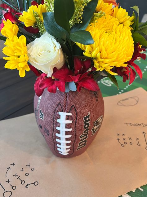 KimberlyMarieLifestyle | looking for the perfect centerpiece for your football themed party? Create this EASY DIY Football vase in a few simple steps and wow your crowd. Floral arranging made easy - combing the gritty with a little grace for your football tablescape. Dinner Banquet Decorations, Football Floral Centerpieces, Football Floral Arrangement, Football Vase Centerpiece, Homecoming Table Centerpieces, Football Flower Arrangements, Tailgate Centerpiece Ideas, Football Theme Centerpieces, Football Diy Decor