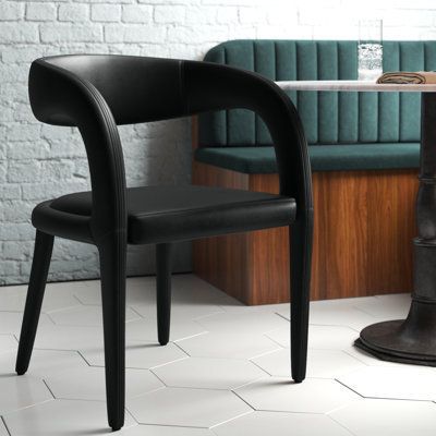 This contemporary dining chair has a sculptural silhouette that we’re quite taken with. Its curvaceous shape is sleek, elegant, a bit edgy – and most definitely distinctive. The rounded legs are angled open back that wraps around like arms, and the seat is padded with foam and wrapped in faux leather in the colour of your choice. Pull this chair up to your desk or consider a set to surround your dining or conference room table. No assembly is required, so you can enjoy it upon receipt. Colour: B Black Wood Chairs Dining Rooms, Barrel Chair Dining Room, Black And White Dining Chairs, Black Modern Dining Chairs, Modern Black Dining Chairs, Curved Back Dining Chair, Black Upholstered Dining Chairs, White Dining Room Sets, Black Dining Room Furniture