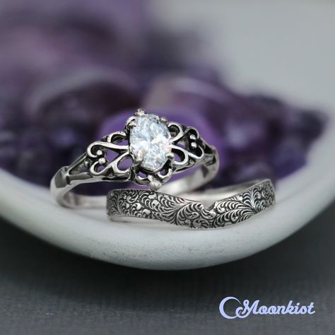 This lovely Vintage Style Filigree Engagement Ring for Women features a sparkling 7 x 5 mm gemstone (approx. 1 ct). The stone is securely set in a 4-prong mounting set in a unique East-West mounting. This sterling silver ring measures 7 mm at its widest point and gently tapers to 2.5 mm at the back of the ring. This accompanying band has a beautiful fern pattern, crafted to have a continuous design that extends around the entire band. This band has been curved and notched to fit more easily with Engagement Ring Sets Vintage, Vintage Engagement Rings Unique 1920s Silver, Hippie Engagement Ring Silver, Vintage Ring Silver, Witchy Engagement Ring Silver, Unique Rings Silver, Fantasy Engagement Rings Silver, Vintage Wedding Ring Set, Nontraditional Engagement Rings Silver