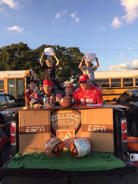 Trunk or Treat College Game Day Style in the pick up. 3 big boxes painted with craft paint. One box opened and spray painted brown for the desk top. 2 painted pumpkins with craft paint. Happy sports fanatics sitting on stools and standing with their team colors and signs. Green blanket and a football to add to the set. The guys guessed the ages of the trick or treat kids rather than the scores of the games. Trunk Or Treat Ideas For Cars Football Theme, Sports Theme Trunk Or Treat, Nfl Trunk Or Treat Ideas, League Of Their Own Trunk Or Treat, College Game Day Trunk Or Treat, Trunk Or Treat Sports Theme, Football Trunk Or Treat Ideas, Football Trunk Or Treat, Church Trunk