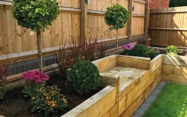 How to Build a Raised Garden Bed with Timber Railway Sleepers | Suregreen's Guide to Raised Beds Raised Garden Beds Along Fence With Seat, Sleeper Beds With Seating, Garden Sleeper Ideas Raised Beds, Timber Sleepers Landscaping, Garden Bed With Seating, Raised Bed With Bench, Diy Raised Garden Bed Along Fence, Raised Beds With Seating, Timber Raised Garden Bed