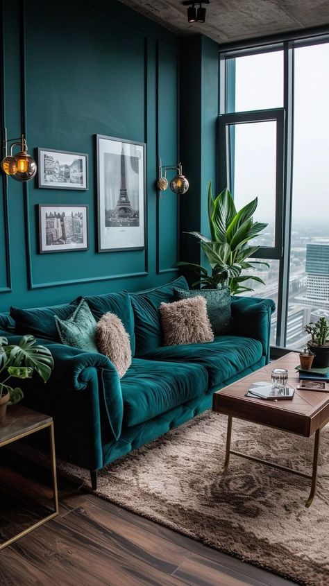 Chic urban living room with teal walls, dark velvet sofa, plush pillows, modern coffee table, framed wall art, and plants in a city apartment. Masculine Living Room Decor, Urban Living Room Decor, Masculine Decor Living Room, Teal Sofa Living Room, Masculine Living Room, Teal Backdrop, Velvet Sofa Living Room, Teal Accent Walls, Masculine Living Rooms