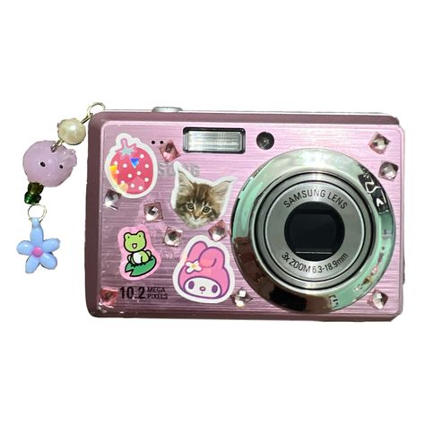 It’s a pink digital Samsung camera with cute stickers placed onto it (my melody, a frog, a cat, and a strawberry) as well as light pink and purple jewels. To the left of it dangles 4 charms connected together by metal loops. The charms are a blue flower, two green small beads, a tiny white pearl, and pink pig bead made of glass Png Aesthetic Camera, Y2k Camera Png, Digital Camera Stickers, Digital Camera Deco, Digicam Sticker, Digital Camera Png Aesthetic, Digital Camera Aesthetic Stickers, Stickers On Digital Camera, Decorated Camera