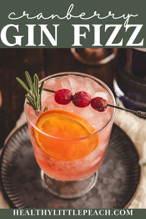 A 5-minute cranberry gin cocktail perfect for the holidays. A combination of gin, citrus juices, cranberry juice, bitters, and ginger beer. Garnished with dried orange, sugared cranberries, and a sprig of rosemary. The best!  Pitcher instructions included. Cranberry Gin Cocktail, Cranberry Gin Fizz, Cranberry Mocktail, Gin Drink Recipes, Unsweetened Cranberry Juice, Gin Fizz Cocktail, Fizz Cocktail, Ginger Cocktails, Cranberry Juice Cocktail