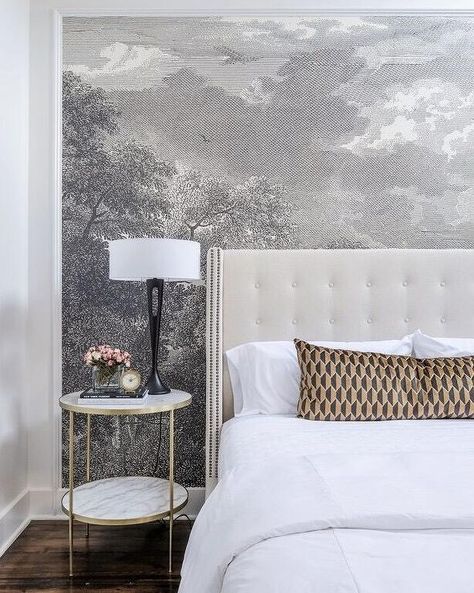 Anthropologie Etched Arcadia Mural is placed in on an accent wall lined with a white tufted wingback headboard with silver nailhead trim on bed dressed in white bedding as well as a gold and black geometric lumbar pillow placed next to a round brass and marble bedside table and a tall eye of a needle lamp. Grey Mural Wallpaper, Gray Tufted Headboard, Gold Wallpaper Bedroom, Headboard And Wallpaper, Wallpaper Headboard, Black Gold Bedroom, Transitional Bedroom, Headboard Wall, White Headboard