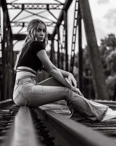 Black and white. Railroad bridge. Jeans and a black half shirt. Blonde girl sitting on railroad bridge. Photoshoot Railroad Tracks, Poses On Railroad Tracks, Photoshoot On Railway Track, Senior Pics On Train Tracks, Senior Picture Ideas On Railroad Tracks, Female Senior Picture Poses Photo Ideas, Cute Senior Photoshoot Ideas, Senior Pictures Women, Railroad Track Photoshoot Senior Pics