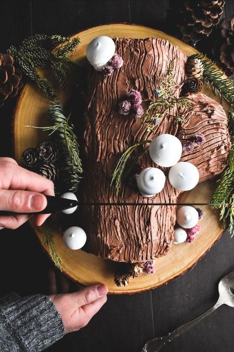 overhead view of a hand holding a knife to slice into a Bûche de Noël cake Yule Logs Decoration, Log Cake Recipe, Roulade Cake, Yule Log Cake Recipe, Fun Holiday Desserts, Meringue Mushrooms, Candied Cranberries, Yule Log Cake, German Baking