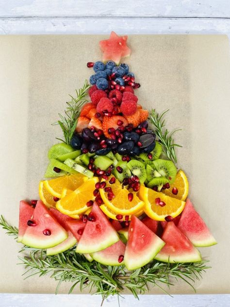 fruit platter being made in shape of Christmas tree - layer of rosemary sprigs, followed by watermelon, sliced oranges, sliced kiwis, sliced grapes, sliced strawberries, raspberries and blueberries with a star on the top cut from a slice of watermelon Natal, Christmas Fruit Snacks, Christmas Fruit Platter, Festive Fruit Platter, Christmas Dessert Platter, Cousins Christmas, Christmas Fruit Salad, Camp Christmas, Christmas Veggie Tray