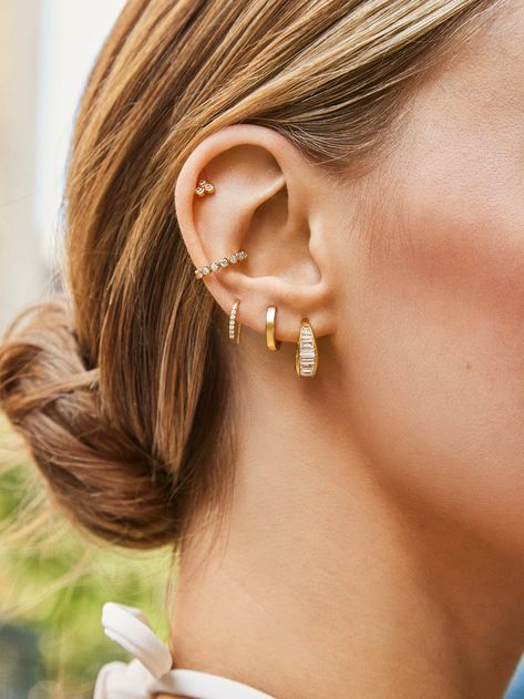 We were dreaming of a pair of chunky hoops with baguette stones, so we made that happen with the Tina 18K Gold Earrings. Crafted from 18K gold plated sterling silver, these contemporary hoops incorporate sleek east-west Cubic Zirconia stones to give this style just the right amount of edge. Earring Stack Inspiration, Top Of Ear Piercing Ideas, Styling Triple Lobe Piercings, Piercings That Go With Conch, Piercing Styling Ideas, Ear Party Piercings, Piercings Styling, Pinterest Ear Piercing, Ear Gold Jewellery