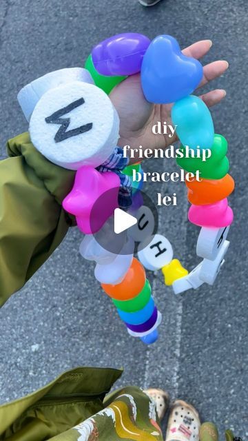 Erica 🌺 on Instagram: "my diy friendship (bracelet) lei 🌺 🩷⭐️🩵

Ⓜ️🩷⭐️ Beads: star/heart shaped ball pit balls, 3x3 in.
styrofoam discs 

🪡: string together using large upholstery needle + 40 lbs fishing line 

Ⓜ️: hand painted on letters 🖊️ 

All materials from Amazon 🛒 

💡 inspo @chelseazeferina 

#graduation #graduationleis #lei #modernlei #leimaking #graduationlei #friendshipbracelets #friendshipbracelet #diy #hawaii #universityofhawaii #oahu" Friendship Bracelet Graduation Lei, Graduation Friendship Bracelets, Friendship Bracelet Lei, Graduation Gift Diy Ideas, Large Friendship Bracelet Garland, Birthday Lei Ideas, Things To Do With Pony Beads, Friendship Bracelet Garland, Craft Ideas For Teens