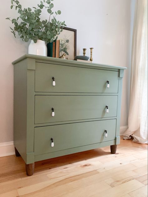 Traditional staging on sage green dresser with dark legs, white drop pulls, vintage print, vintage books, and greenery #painted #dresser #green Green Dresser Decor Bedroom, Earth Tone Furniture Paint, Dresser Drawer Colors, Dresser Vintage Decor, Accent Color Dresser In Bedroom, Green Dresser Black Hardware, Diy Dresser Makeover Sage Green, Sage Colored Furniture, Green Dressers Bedroom