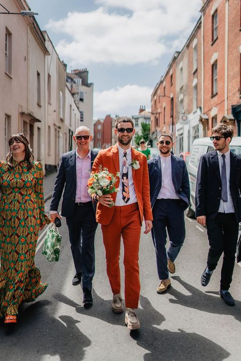 Groom in orange suit with patterned tie and white flower buttonhole and sunglasses walking with groomsmen in suits and sunglasses for Bristol city wedding Mens Colored Suits Wedding, Non Traditional Suit Men, Men’s Wedding Suits 2023, Wedding Suits Men Colourful, Funky Wedding Suits Men, Mens Mismatched Suits, Coloured Wedding Suit, Fun Groom Suit, Coloured Groom Suit