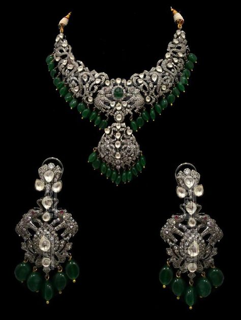 "Israh Victorian Emerald Bridal Set This traditional yet very trendy silver and kundan number is perfect for your wedding attire.This set features a choker style necklace with polki detailing. This Emeralds & Victorian setting stunning necklace set is made of copper+silver alloy with white kundan stones, which are covered in silver foil. The set has a stunning emerald pendant and matching earrings. The whole process is the traditional jadau process of making jewelry. Elevate your style quotient Victorian Style Necklace, Silver Victorian Jewelry, Victorian Sets Jewellery, Victorian Antique Jewelry, Victorian Gold Jewelry, Victorian Diamond Jewellery, Vintage Necklace Victorian, Victorian Polki Jewellery, Victorian Jewelry Indian