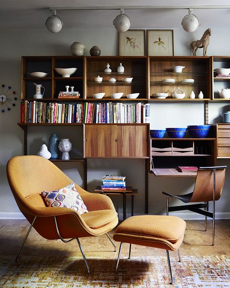 Illuminated by track lighting, a teak wall unit by Poul Cadovius showcases pottery by Eva Zeisel and Paul McCobb, among others. The desk seat is a T chair by William Katavolos, Ross Littell, and Douglas Kelley; the Womb chair is by Eero Saarinen for Knoll. Poltrona Design, Small Basement Remodel, Chair Design Modern, Womb Chair, Mid Century Living, Mid Century Living Room, Mid Century Modern Living, Mid Century Modern Interiors, Florence Knoll