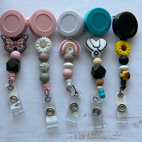 Who says wearing a badge has to be boring? Retractable badge reels are super fun accessory for Teachers, Nurses, Health care workers and other professions! Silicone beads and Natural Wood beads make a statement - customize one today. They are light weight, and have an alligator clip with 360o swivel for a secure and flexible attachment. It extends and retracts effortlessly. Badge reel colors currently available are White, Pink, Blue (deep turquoise blue) and Black. These badges shown have alread Making Silicone Bead Keychains, Silicone Badge Reel, Silicone Bead Badge Reel, Silicone Bead Ideas, Diy Badge Reel, Journal Dangles, Badge Charms, Crafts Keychains, Silicone Bead Lanyard