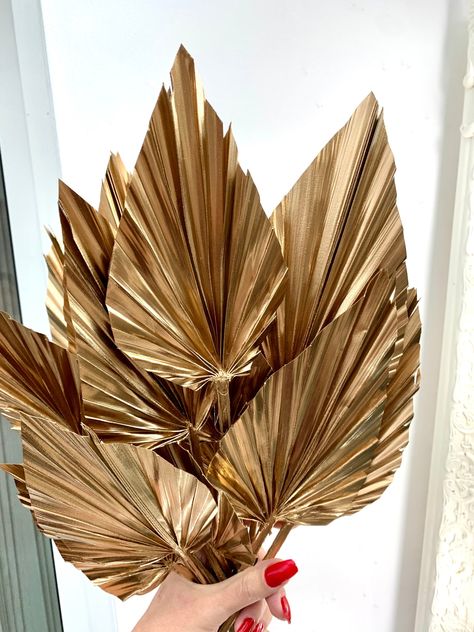 5 Gold Palm leaves, Medium, 8-12 cm leaf width, amd 30cm overall length. This is our Dried Palm Leaf, Gold Colour. It is exotic and trendy. 5 stems in a bunch. We feel this great Palm Sun would make a perfect addition to any dried or fresh arrangement, on its own in a vase, as a cake topper and for any event decoration. These can also be used in many different applications for floral uses and in crafting as it makes a great imprint. SPECIAL PRICE FOR WHOLESALE ORDERS. Message us for more info . Dried Palm Leaf Decor, Palm Leaf Centerpiece, Dried Flowers Cake, Gold Palm Leaves, Palm Leaf Decor, Palm Tree Decorations, Palm Tree Leaves, Leaf Plates, Event Decoration