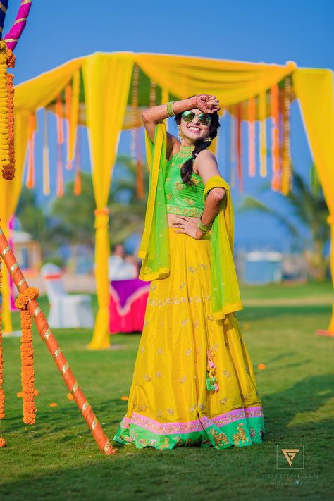 When a bride as cool and as fun as Teju is planning her Mehendi, we must feature the grand fun-o-holic event!  The stunning bride doesn’t overload herself with loads of jewels; instead, she keeps it chic and simple with dangling earrings, glittering bangles and a pair of swaggy aviators. To add to her cuteness, lovability and charm the funny photo booth props are doing just the trick.  The decor and theme are inspired by the new-age funky touch, it features g... Mangalasnanam Stills, Haldi Poses For Bride, भारतीय दुल्हन संबंधी, Haldi Photoshoot, Funny Photo Booth, Haldi Ceremony Outfit, Indian Bride Poses, Indian Bride Photography Poses, Bridesmaid Photoshoot