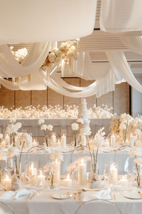 All white wedding. White Pillar Candles, white garden roses and orchids, and gold silverware. White Cream Ivory Wedding, Off White Wedding Decorations, Minimal Center Piece Wedding, White And Candle Wedding, Ivory Party Decorations, White Neutral Wedding Decor, Elegant Wedding Styling, White And Glass Wedding Decor, Rose Gold White Wedding Decor