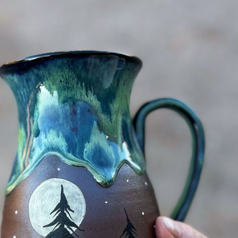 SamandMo Pottery on Instagram: "Natural light shows off the colors on this Northern Lights mug and its nice chunky drips!😊 we will have some more of these available in our April restock 😊  #northernlightscanada #northernlights #northernlightsart #tree #treelovers #forest #mug #cup #art#handpainted #pottery #ceramicmug #rustic #unique #ceramics" Drawing On Pottery, Northern Lights Canada, Forest Mug, Northern Lights Art, Pottery Lighting, Pottery Items, Glaze Combinations, Tree Mug, Pottery Design